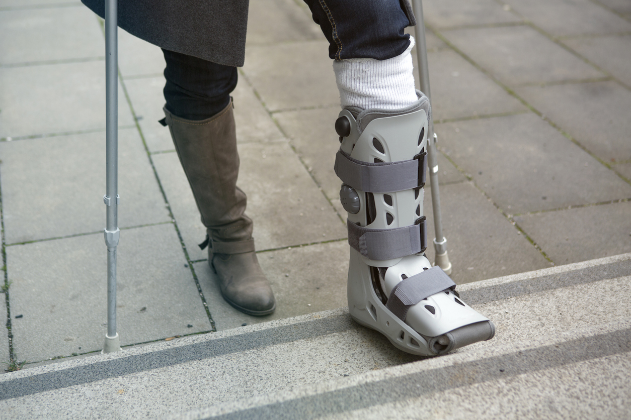 woman walking on crutches with a medical boot on foot